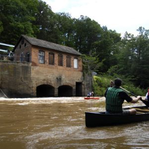 Paddlers on the South Fork River look at a small independent hydro power generating plant on the river