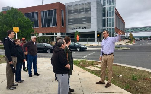 On a May 13 walk, leader Tobe Holmes of University City Partners, in front of a new Charlotte Area Transit System parking deck, describes changes that will make North Tryon Street a more pedestrian-friendly area when the Blue Line Extension opens March 2018. Photo: Mary Newsom