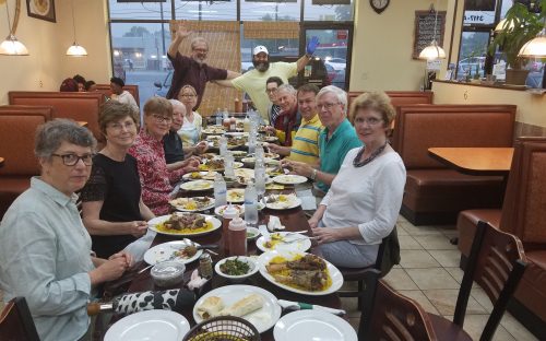 The first walk, May 1, was a Munching Tour of east Charlotte, led by historian Tom Hanchett, at far end of table, left. The group is at La Shish Kebob, with owner Izzat Freitekh, at end of table, right, waving with blue glove. Photo: Angelique Gaines.