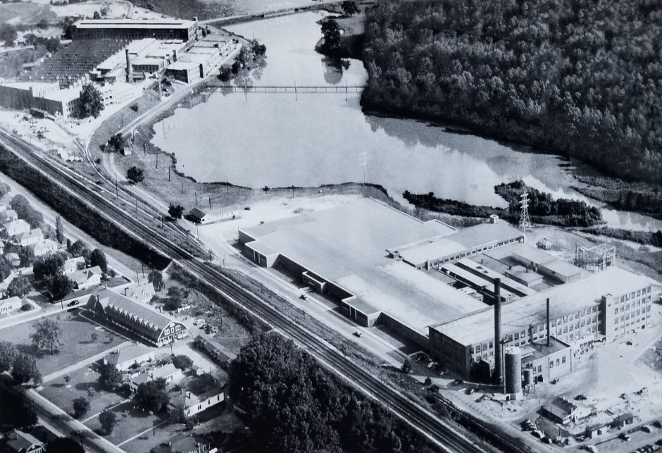 The Mays and Mayflower mills in Cramerton, both of which closed in the 1970s. One was subsequently demolished, the other destroyed by fire. In this photo, the South Fork of the Catawba River has been diverted to form a wide pool to serve the mills' dyeing and finishing operations. Waste dumped in the water gave it the nickname "Rainbow River" for decades. To the left of the train tracks, a dormitory for single, male mill workers is visible; above those, mill houses can be seen. Photo courtesy the Millican P