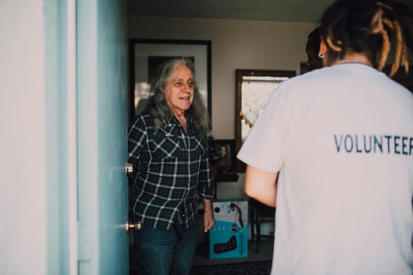 Elderly woman opening her door to volunteers.