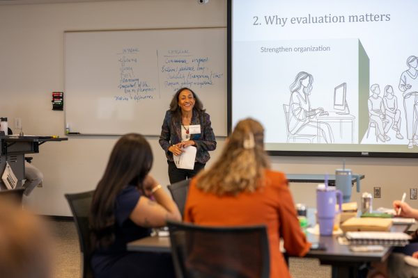 An woman leads instruction of a workgroup from the front of the class.