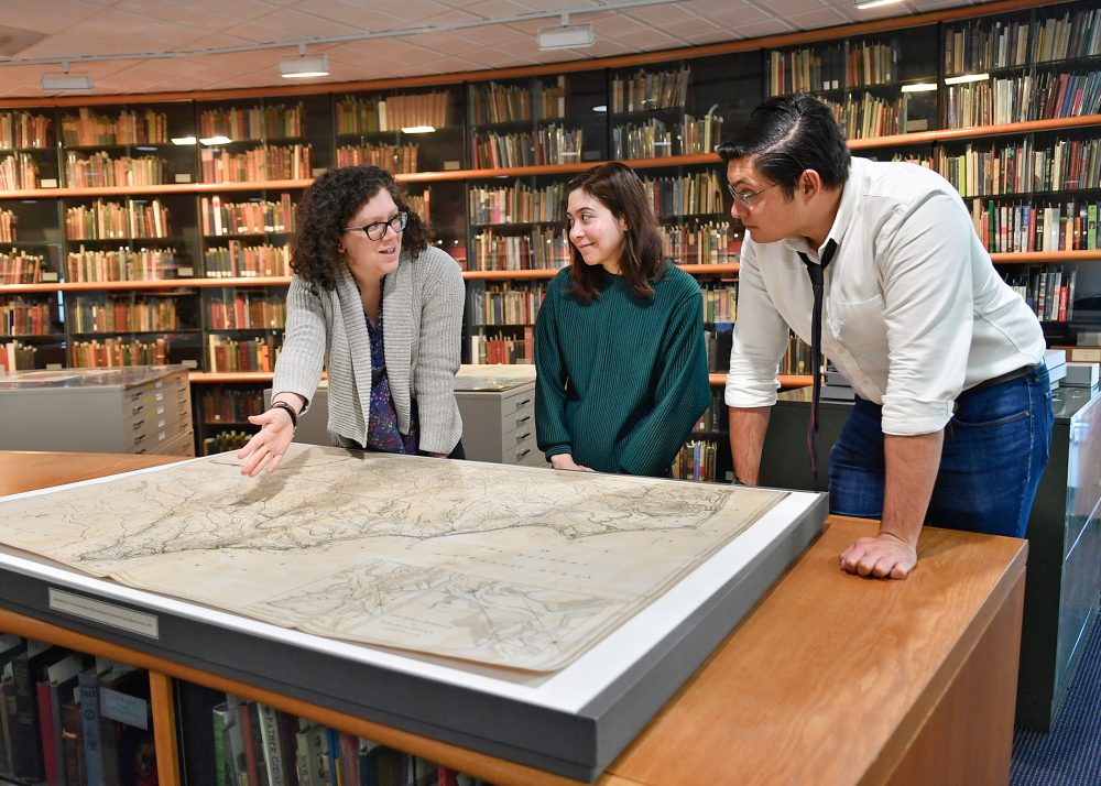 A group of students review a map with a UNC Charlotte library staff member.